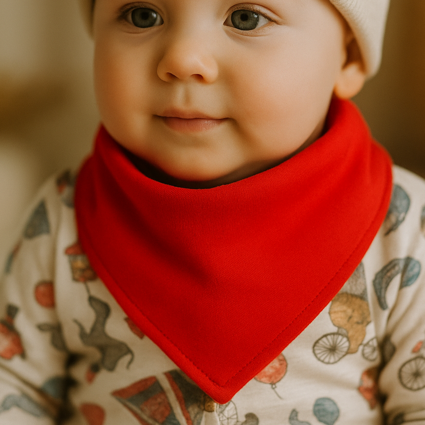 Bandana babador de bebê na cor vermelha, feita em malha de algodão premium, com acabamento minimalista e botões de pressão para ajuste, fotografada com luz natural e sombras suaves.

