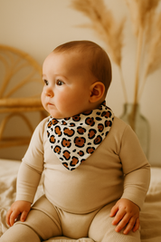 Bebê usando bandana babador com estampa de oncinha neutra, feita em algodão stretch premium, look minimalista e elegante.

