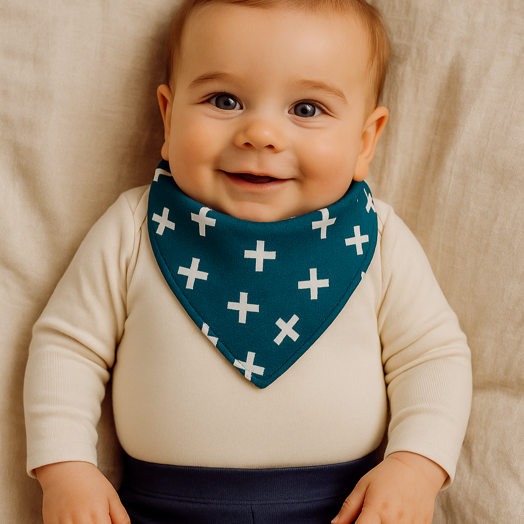 Bebê de 9 meses usando bandana azul com cruzetas brancas, em ambiente boho chic com luz natural suave, cercado por elementos em madeira e plantas.

