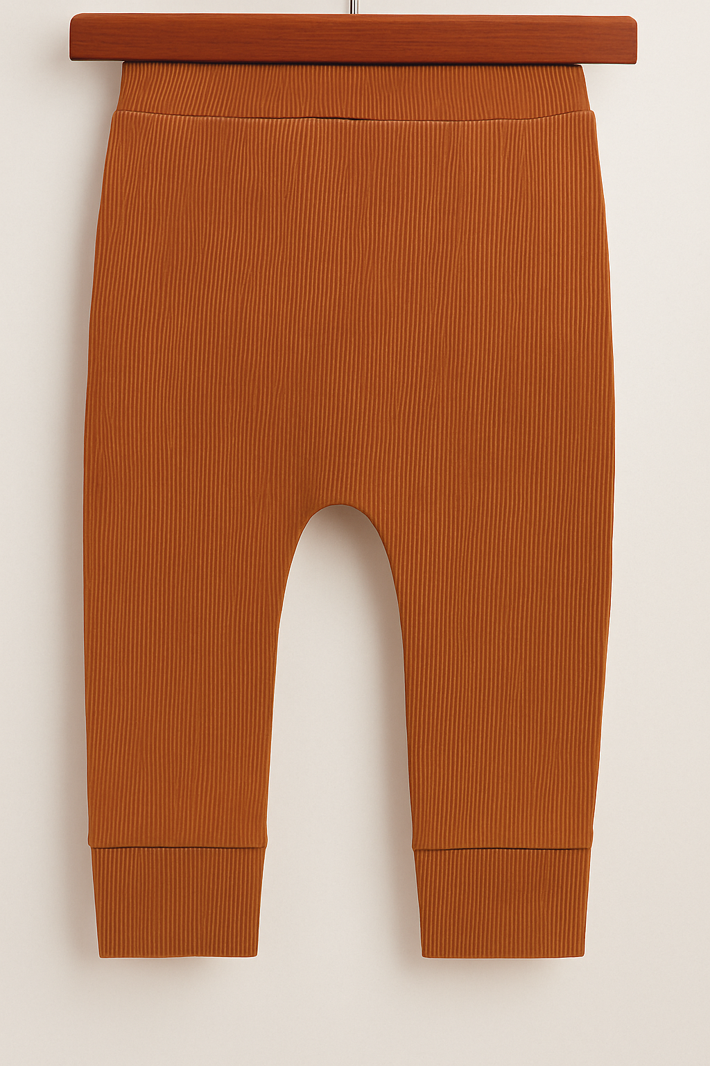 Calça bebê de tecido canelado na cor telha, com cós largo e acabamento confortável sem bolso.