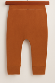 Calça bebê de tecido canelado na cor telha, com cós largo e acabamento confortável sem bolso.