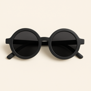 Óculos de sol infantil redondo com armação preta fosca e lentes escuras, modelo unissex da marca Means Love Baby