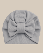 Bebê de 1 ano ao ar livre usando turbante azul serenity com laço, vestindo roupa neutra que combina com o acessório.